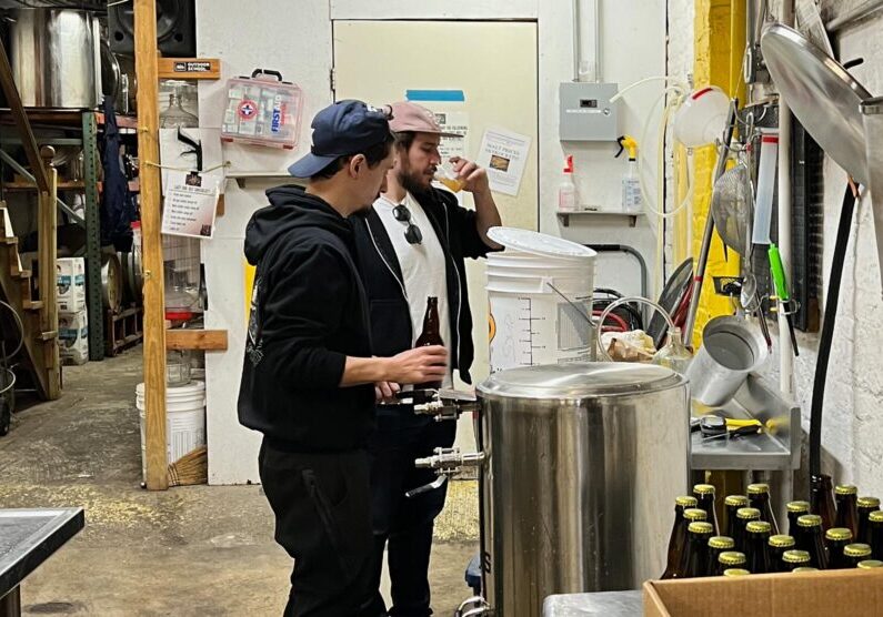 Photo of two CHAOS brewing members bottling a batch of beer.